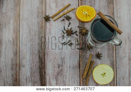 Hot Mulled Wine Drink With Lemon, Apple, Cinnamon, Anise And Other Spices In A Glass Cup Between Fir