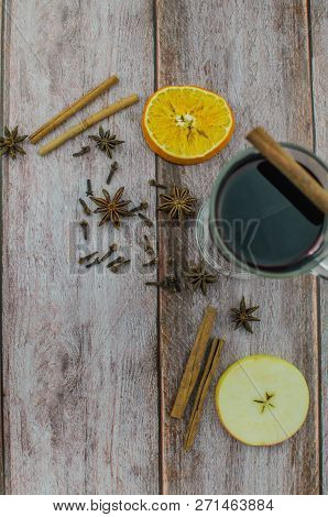 Hot Mulled Wine Drink With Lemon, Apple, Cinnamon, Anise And Other Spices In A Glass Cup Between Fir