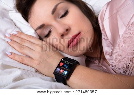 Beautiful Woman Sleeping On Bed With Smartwatch Showing Heartbeat Rate