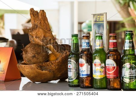 Crete, Greece - July 31 2018: Glass Beer Bottles On A Counter With Exotic Coconut Decoration.