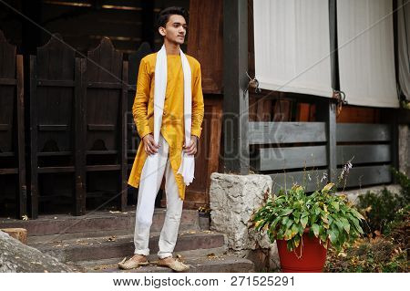 Indian Stylish Man In Yellow Traditional Clothes With White Scarf Posed Outdoor.