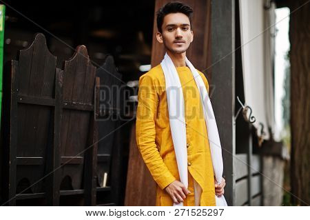 Indian Stylish Man In Yellow Traditional Clothes With White Scarf Posed Outdoor.