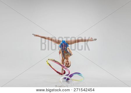 The Portrait Of Beautiful Young Brunette Woman Gymnast Training Calilisthenics Exercise With Blue Ri