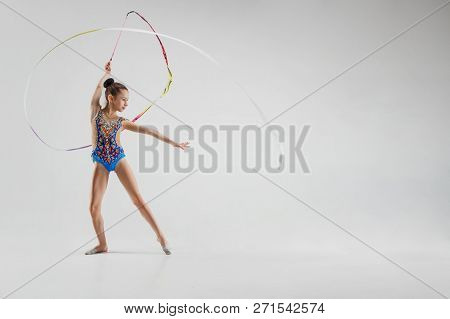 The Portrait Of Beautiful Young Brunette Woman Gymnast Training Calilisthenics Exercise With Blue Ri
