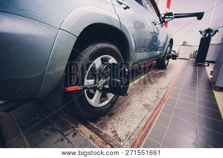 Mechanic Tuning Aligner For Wheel Alignment In Garage Closeup. Professional Car Maintenance In Moder