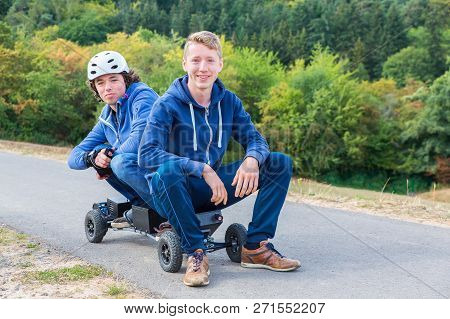 Two Young Dutch Men Sitting Together On Mountainboard In Nature
