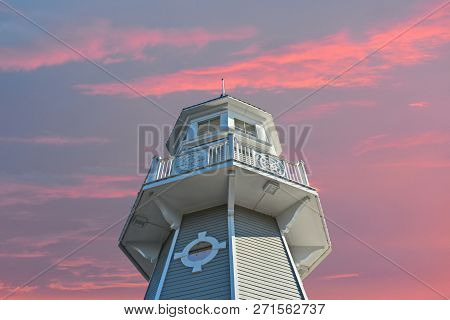 Orlando, Florida. November 15, 2018 Top View Of Lighthouse On Lightblue Sky And Magenta Clouds Backg