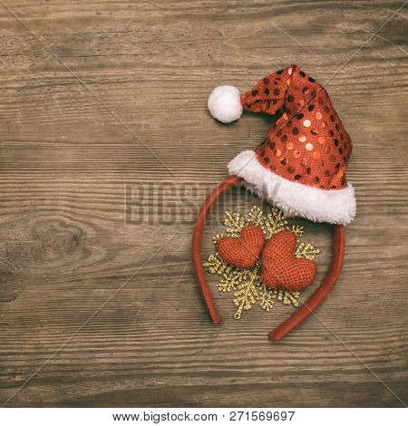 Background Christmas Decoration Red Cap Of Santa And Two Hearts On Wooden Table.