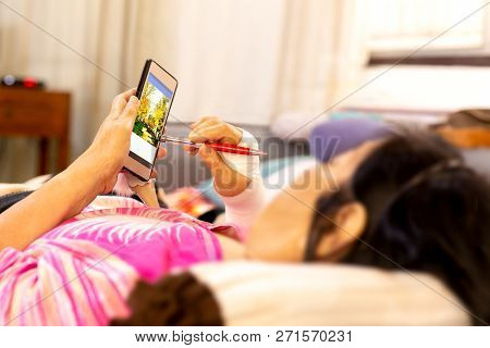 Senior Patient Hand Injured With Bandage Lying Down And Using Cell Phone.