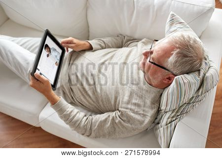 technology, e-learning and education concept - senior man watching business webinar on tablet pc computer at home
