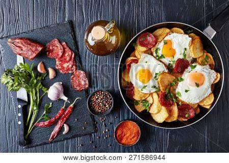 Traditional Spanish Huevos Rotos - Fried Eggs With Potatoes, Pork Sausages Chorizo In A Skillet On A