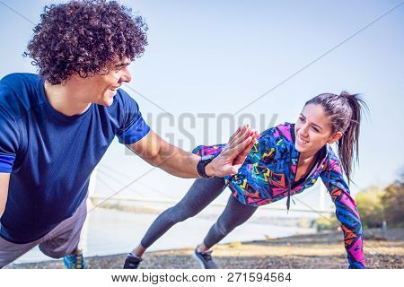 Young Athletes Giving High Five To Each Other While Doing Push-ups Outdoors