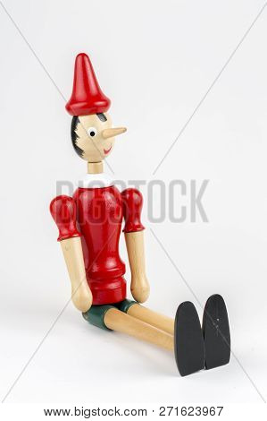 Wooden Pinocchio Doll Sitting Isolated On White Background.