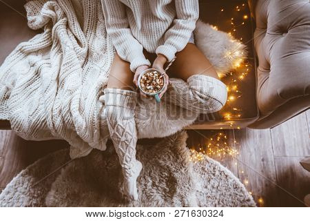 Cold autumn or winter weekend while drinking warm cocoa with marshmellows. Lazy day in knitted socks on the couch. Cosy scene, hygge concept, top veiw.