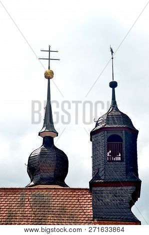 Two Towers Are On The End Of A Roof. One Has A Golden Orb And Double Cross. The Other Is Bell Tower.
