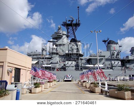 Honolulu - April 26, 2010: Row Of Usa Flags Leading To The Uss Missouri With Radar And Satellite Tow