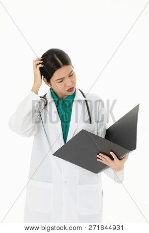 Asian Female Docter Is Working On Patient File. In Uniform And Astethoscope On Shoulder, Isolated In