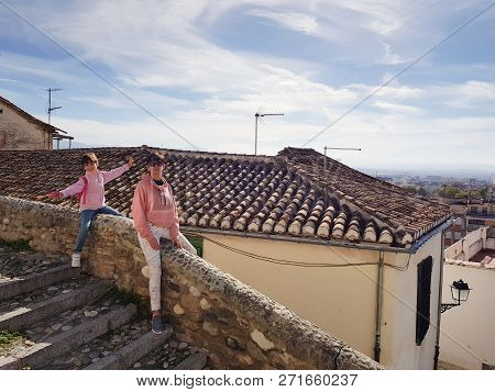 Mother And Daughter Sitting On A Balcony Enjoying The Views Of Granada From The Realejo Neighborhood