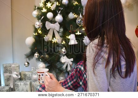 Beautiful Woman Under A Christmas Tree. Girl Veit A New Year And Drink Coffee Under Christmas Tree