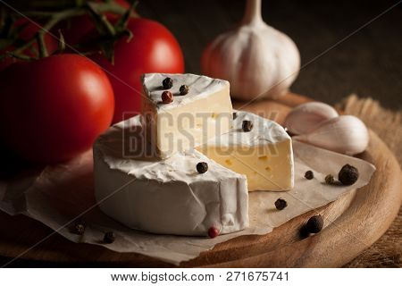 Camembert And Brie Cheese On Wooden Background With Tomatoes, Letuce And Garlic. Italian Food. Dairy