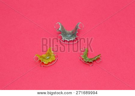 Colorful Dental Braces Or Retainers For Teeth On Pink Background, Closeup