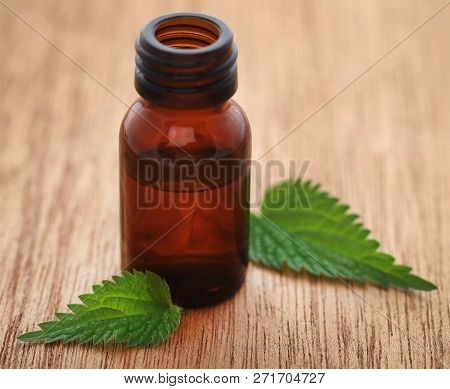 Nettle Leaves With Extract In A Bottle On Wooden Surface