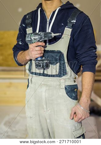 Worker In Dirty Uniform Or Boilersuit  With Drill In His Hand In The Room Of Apartment  That  Is Und