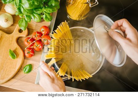 Process Of Cooking Homemade Italian Pasta. Lifestyle Background. Man Droping Spaghetti Into Boiling 