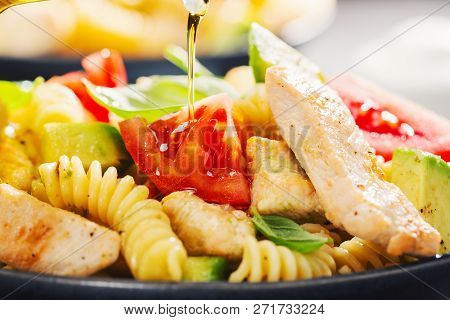 Pouring Olive Oil On Tasty Fresh Made Italian Pasta Salad With Fusilli Al Bronzo, Tomatoes, Avocado,
