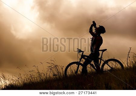 Attractive, healthy couple drink from their water bottles on mountain bikes. active outdoor lifestyle concept