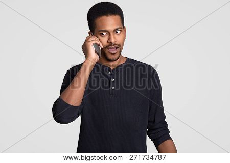 Embarrassed African American Man Has Telephone Coversation Indoor, Discusses Something Unpleasant An
