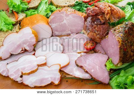 Assortment Of Meat Products Including Ham And Sausages With Greenary And Spices On Wooden Table Clos