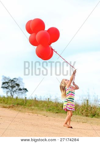 Genç beyaz kız Beklemeler sıkıca helyum bir demet kırmızı balon dolu