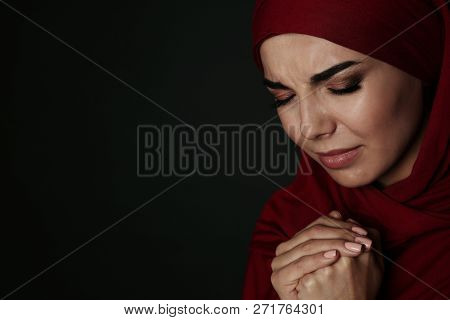 Portrait Of Sad Muslim Woman In Hijab  Praying On Dark Background. Space For Text