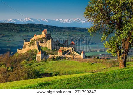 Fantastic Travel Place, Gorgeous Rupea Fortress With High Snowy Mountains In Background, Transylvani