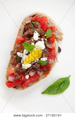 Closeup köstliche Oliven Tapenade Tomate Bruschetta mit Feta-Käse und frischem Basilikum Blätter.