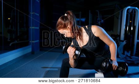 A Girl Performs A Concentrated Bench Press Sitting With The Help Of Dumbbells.