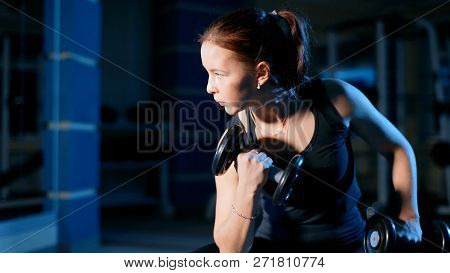 A Girl Performs A Concentrated Bench Press Sitting With The Help Of Dumbbells.