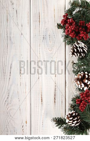 Spruce Branches, Cones And Red Berries On A White Wooden Background. Background For Christmas And Ne