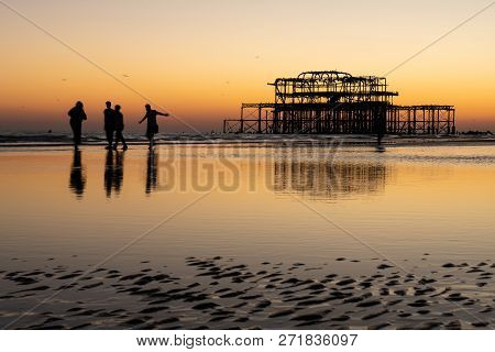 The Old Remains Of Brighton Pier Left Standing In Sea With Beautiful Waves, Seagulls And Local Peopl