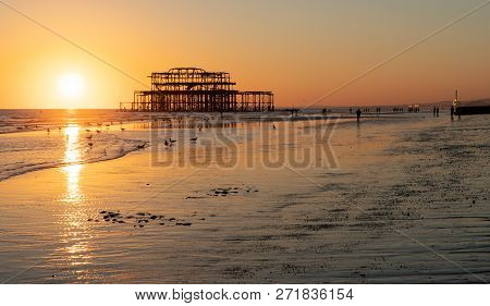 The Old Remains Of Brighton Pier Left Standing In Sea With Beautiful Waves, Seagulls And Local Peopl