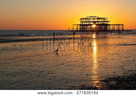 The Old Remains Of Brighton Pier Left Standing In Sea With Beautiful Waves, Seagulls And Local Peopl