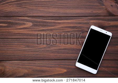 Mobile Phone With Blank Screen On Brown Wooden Table. Smartfone White