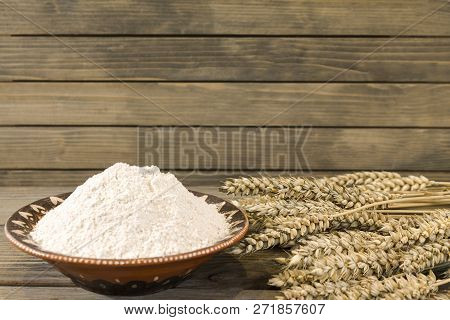 Wheat Spikelets And Flour On Wooden Plank Background