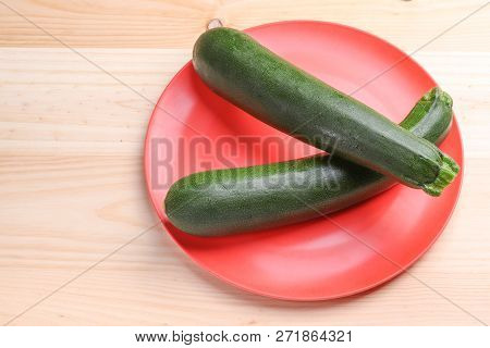 Fresh Zucchini On A Red Plate And Wooden Background. Healthy And Healthy Food.