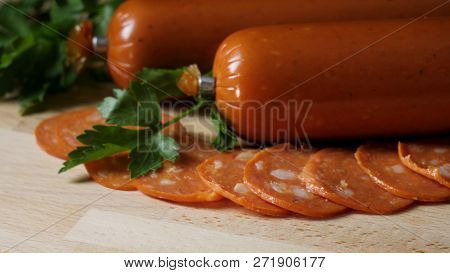 Dried Organic Salami Sausage On Wooden Cutting Board. Frame. Sausage On A Wooden Board With Rosemary