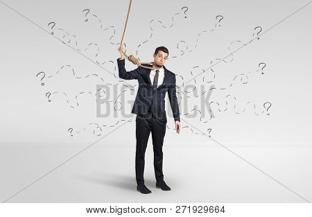 Hopeless young businessman trying to suicide with question signs concept