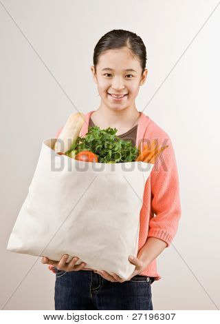 สาวมั่นที่ถือถุงชำที่เต็มไปด้วยผักและผลไม้สดบริสุทธ์