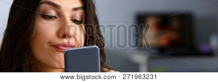 Young Beautiful Businesswoman Unhappily Holding Smartphone In Her Hand Contemptuously Looks At Displ