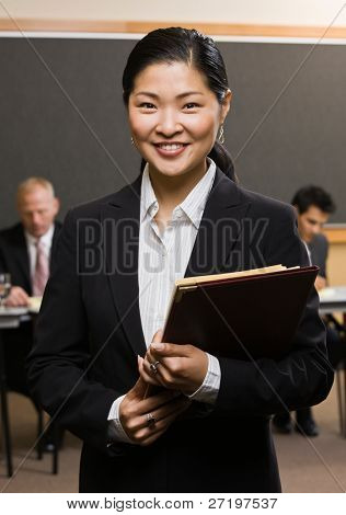 มั่นใจนักธุรกิจเอเชียถือแฟ้มหน้าเพื่อนร่วมงานในห้องประชุม
